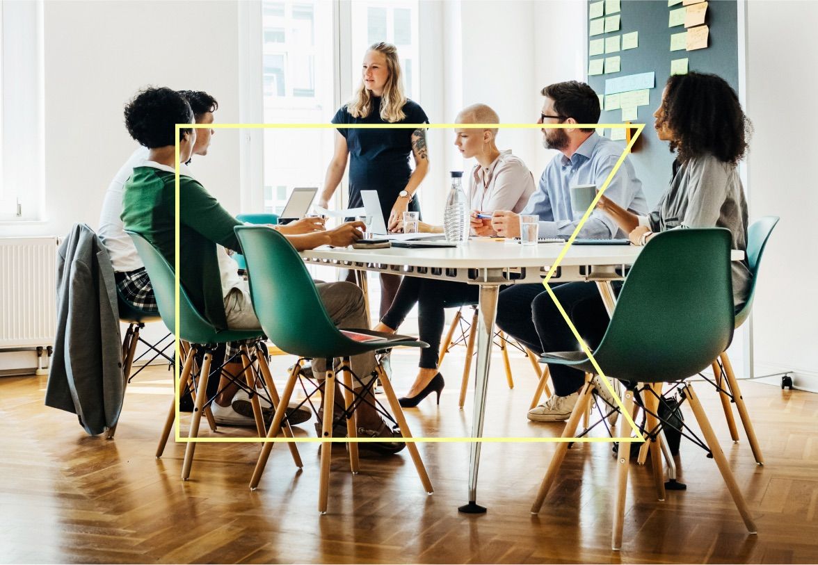 Several people sitting around a desk in a workplace setting