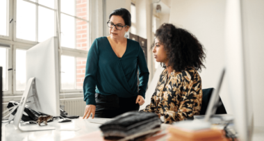Senior businesswoman helping young colleague in office
